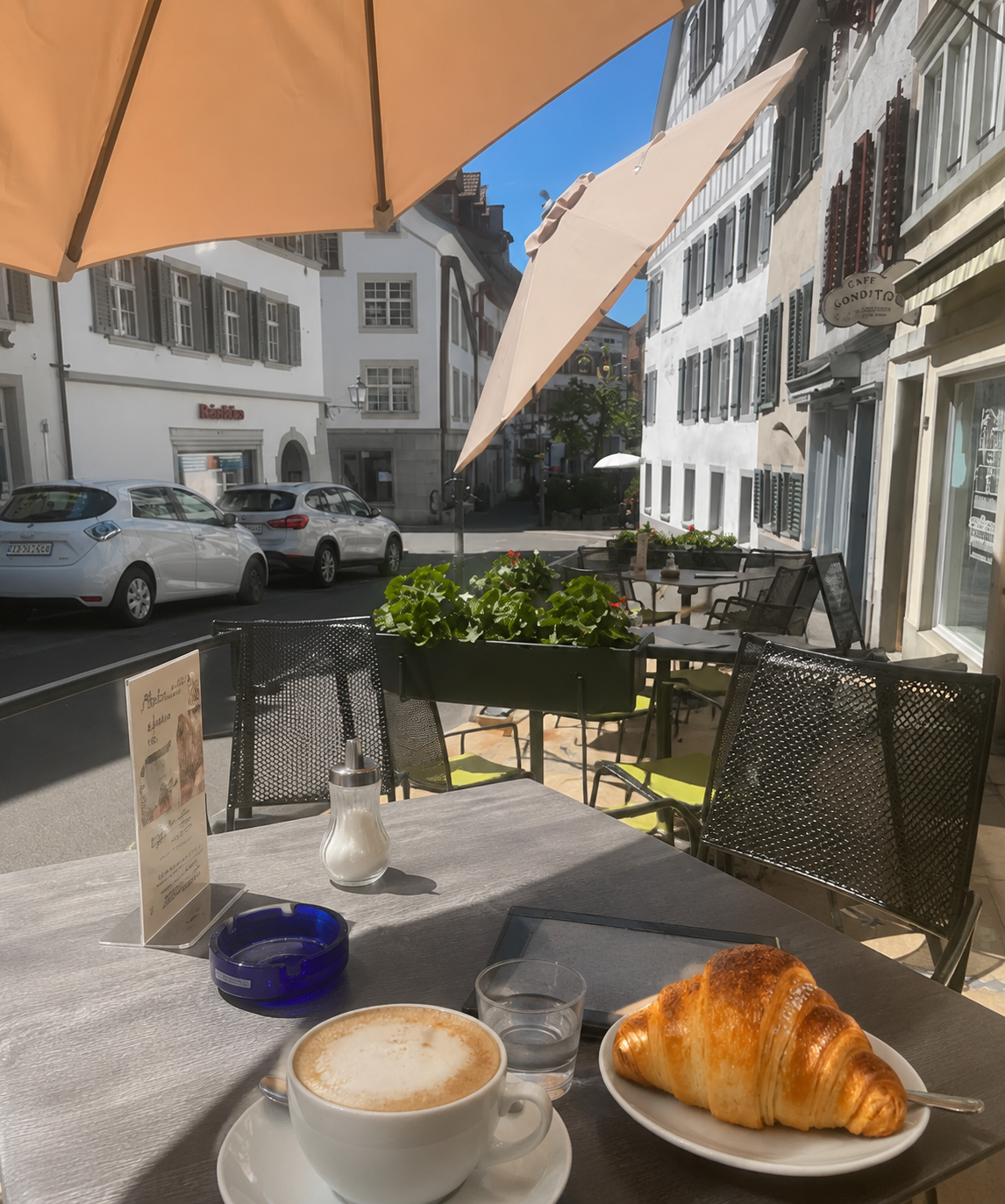 Sommerliche Terrasse von Es Stückli Himmel mit Sonnenschirm, Kaffee und Gipfeli, Blick in die Altstadt von Bischofszell